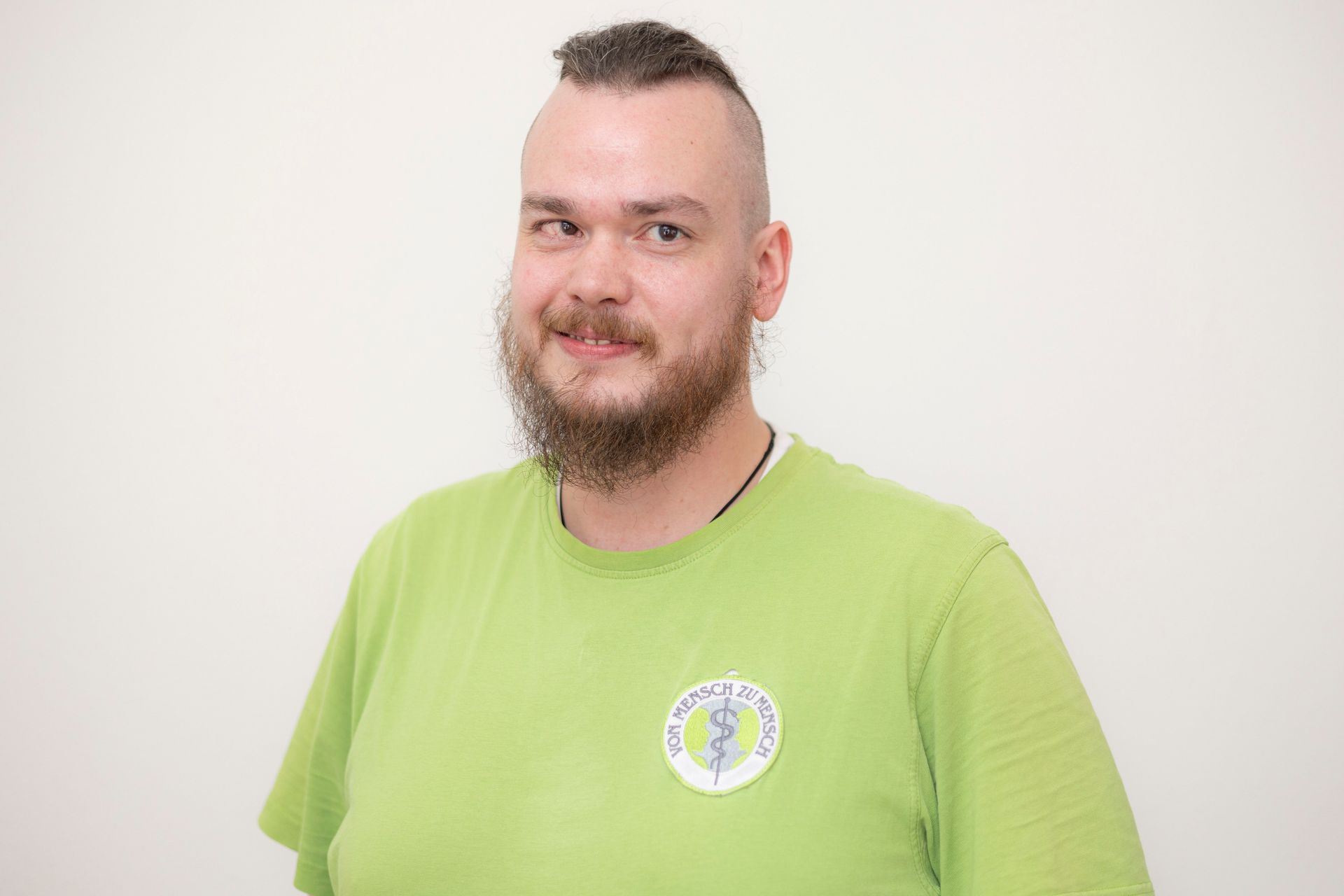 Ein Mann mit Bart und Schnurrbart trägt ein grünes Hemd.