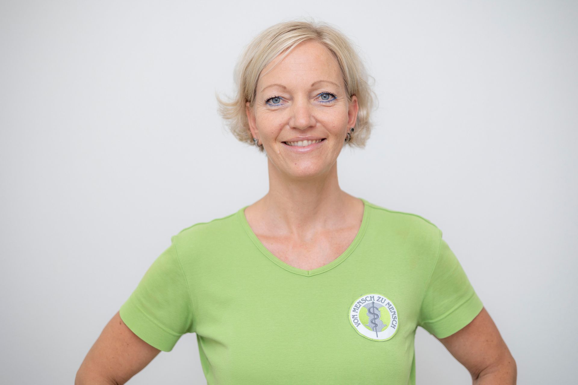 Eine Frau trägt ein grünes T-Shirt und lächelt.