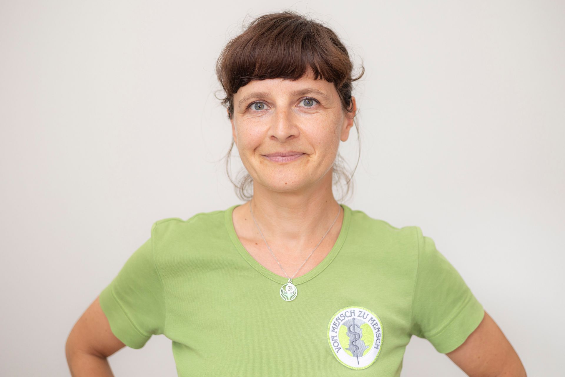 Eine Frau trägt ein grünes T-Shirt und lächelt.