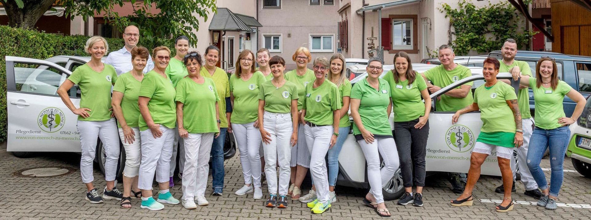 Eine Gruppe von Menschen in grünen Hemden und weißen Hosen posiert für ein Foto.
