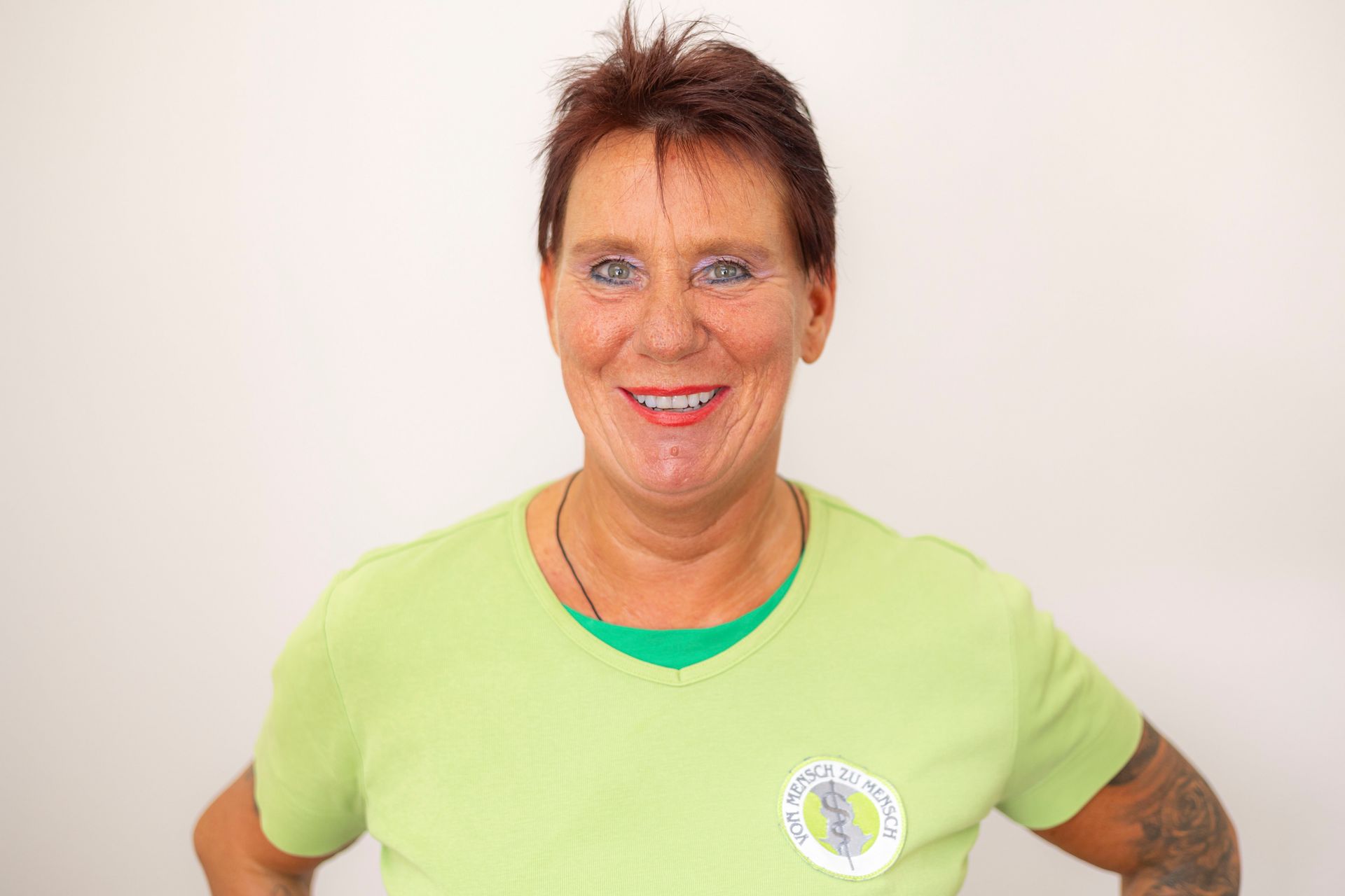 Eine Frau trägt ein grünes Hemd und lächelt in die Kamera.