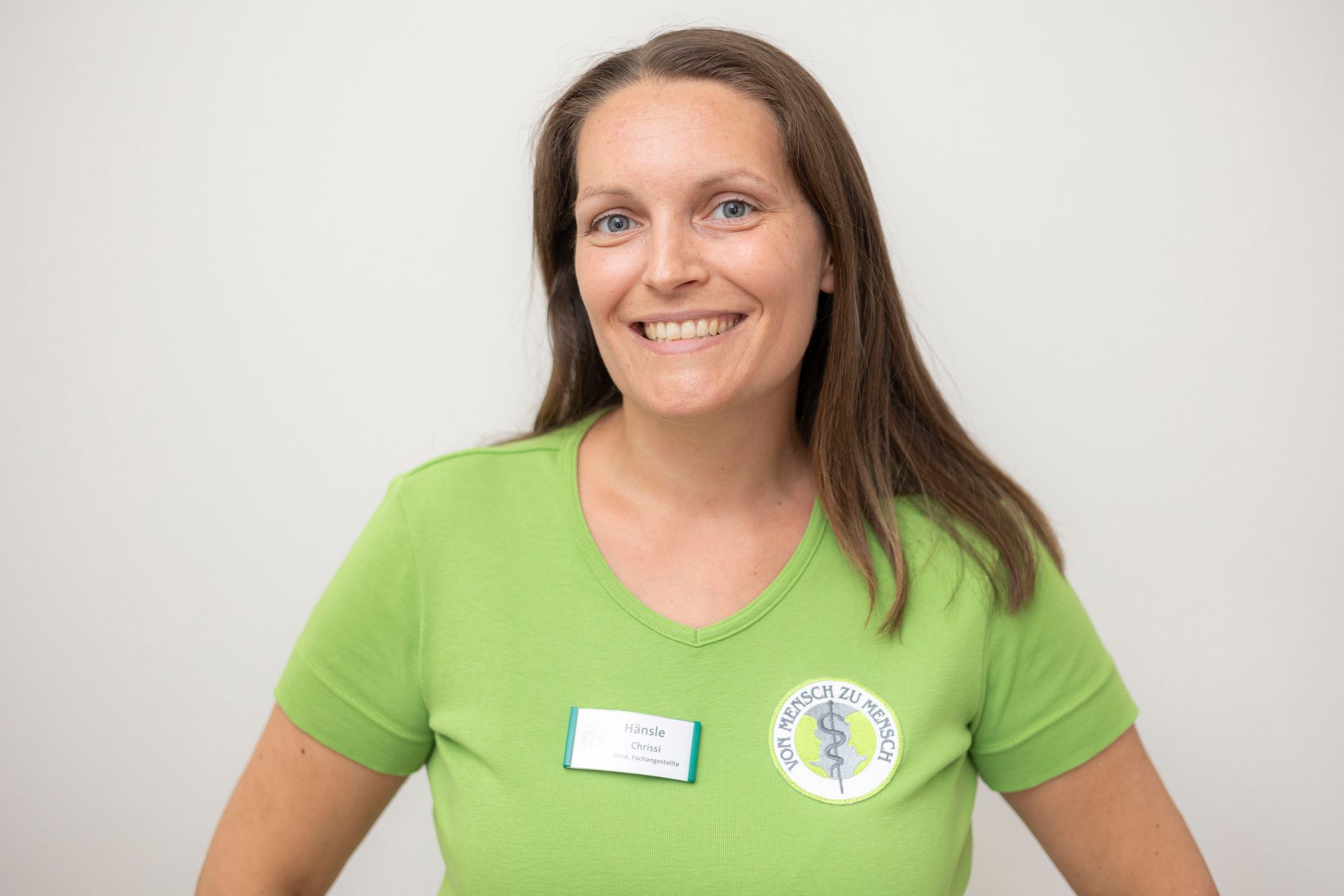 Eine Frau trägt ein grünes Hemd und lächelt.