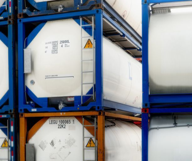 A stack of blue and white shipping containers with a yellow warning sign on the side