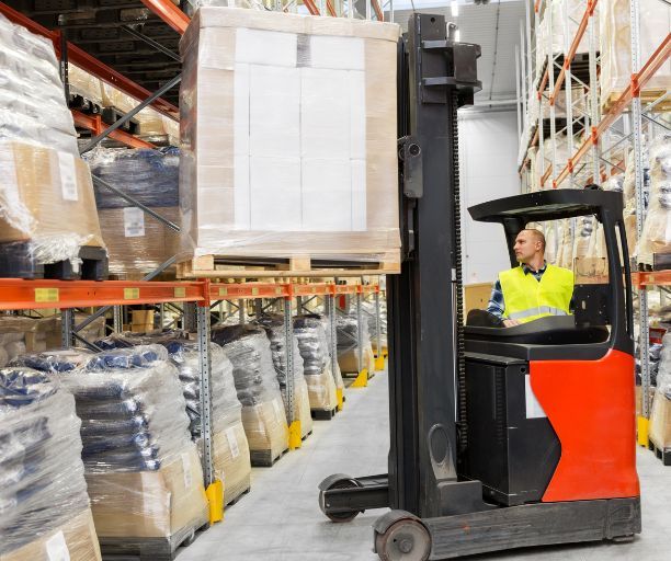 A man is driving a forklift in a warehouse.