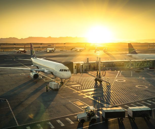 An airplane is parked on the tarmac at an airport at sunset.