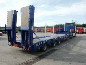A blue trailer is parked in a parking lot next to a truck.