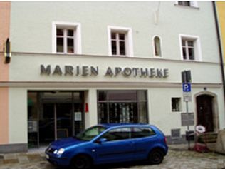 Ein blaues Auto parkt vor dem Gebäude der „Marien Apotheke“ in Deutschland.