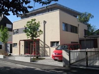 Beiges, modernes Gebäude mit einem davor geparkten roten Lieferwagen.