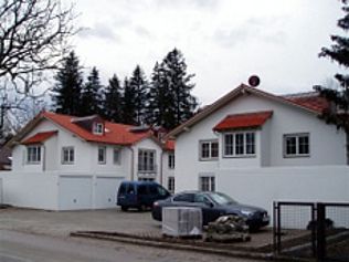 Weiße Häuser mit roten Ziegeldächern, davor parkende Autos.