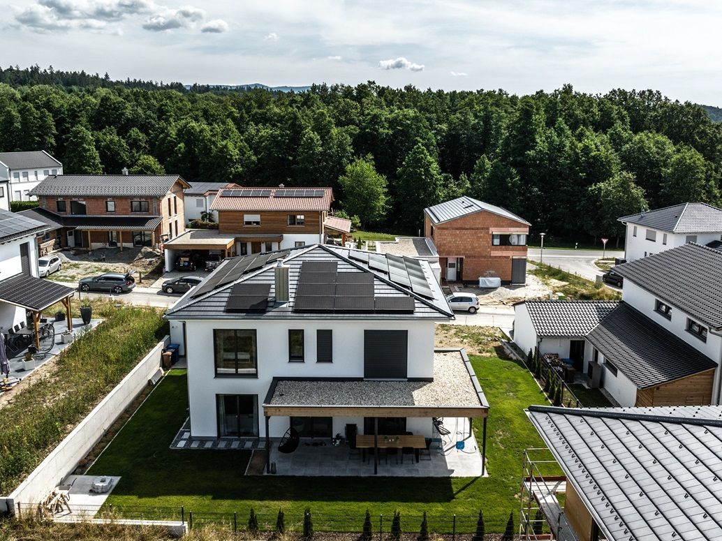 Häuser in einem Viertel mit Solarzellen auf dem Dach, umgeben von Bäumen.
