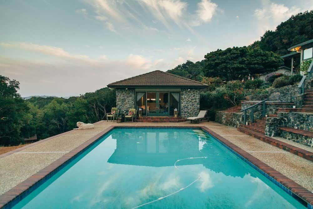 Infinity pool overlooking a tropical hillside villa at sunset