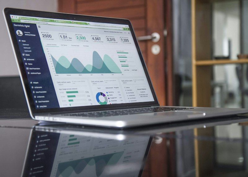 Laptop showing an analytics dashboard with charts on a glass table