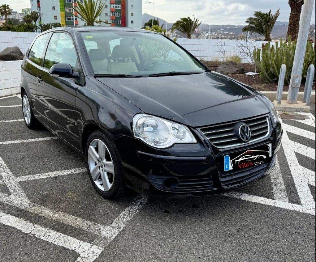 Volkswagen Polo negro aparcado en una plaza de aparcamiento marcada.