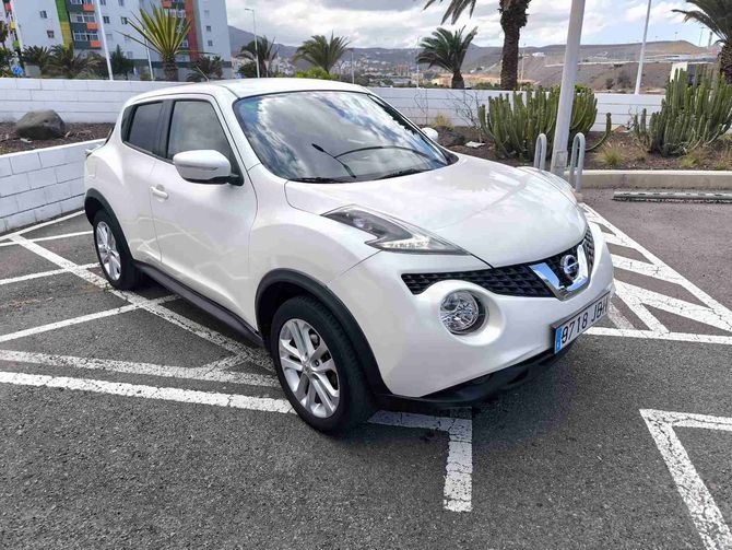 Vehículo todoterreno Nissan Juke de color blanco estacionado en un espacio de estacionamiento.