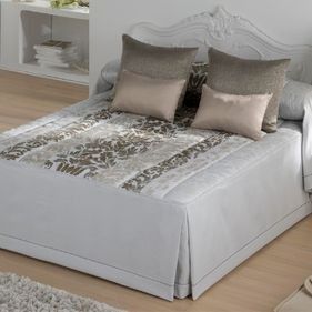 Una cama con un edredón blanco y almohadas en un dormitorio.