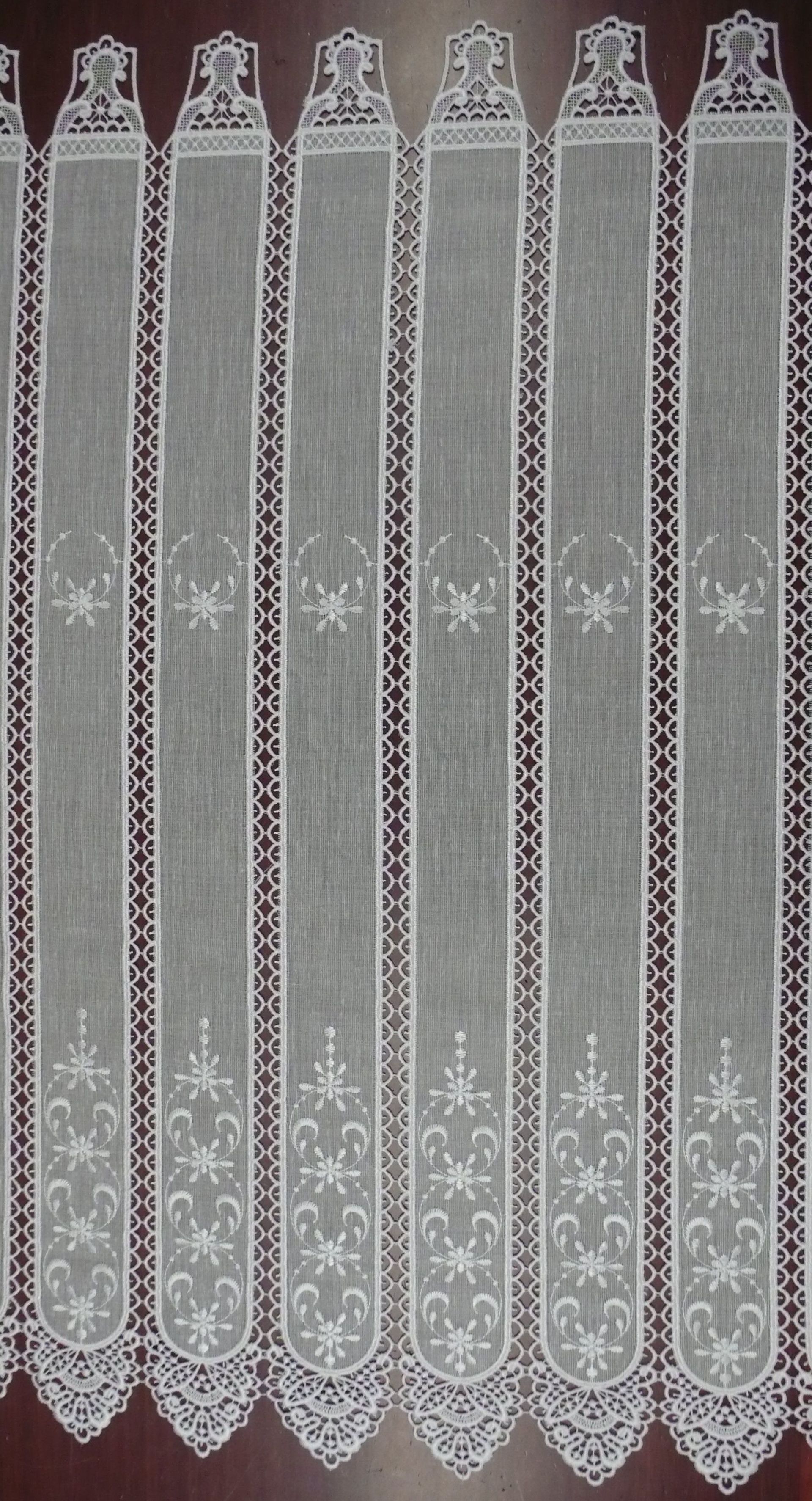 Un primer plano de una cortina de encaje blanco sobre un fondo marrón.