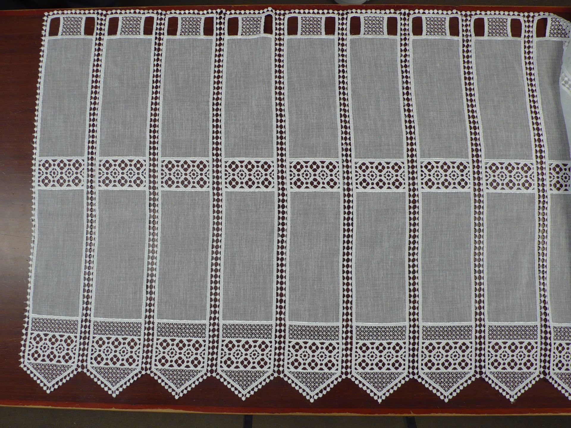 Una cortina de encaje blanco está sobre una mesa de madera.