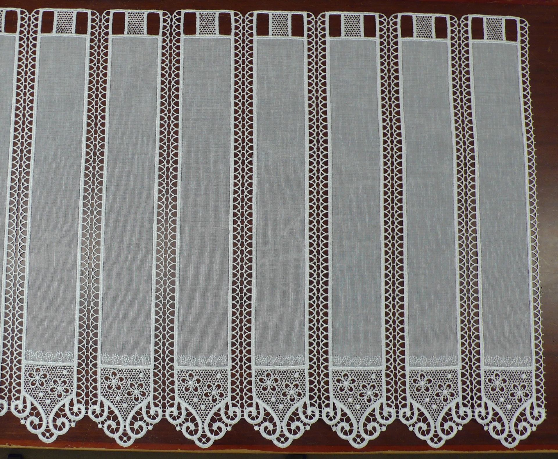 Una cortina de encaje blanco está sobre una mesa de madera.