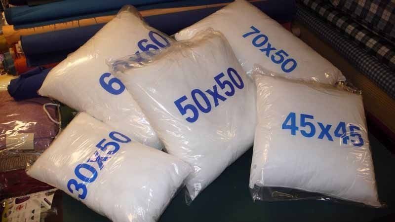 Una pila de almohadas blancas con letras azules sobre ellas están sobre una mesa.