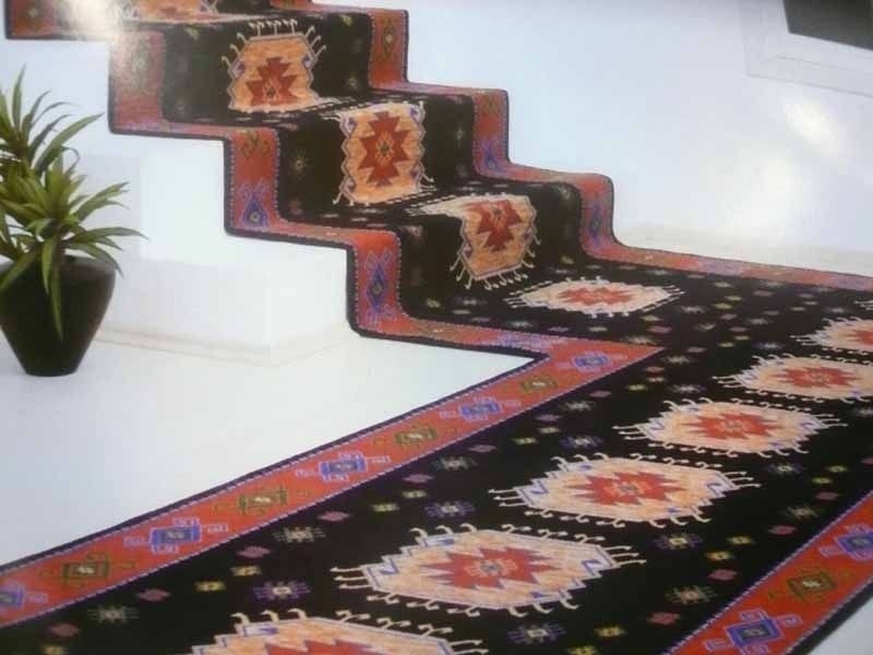Una escalera con una alfombra y una planta al fondo.