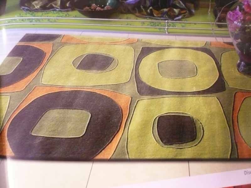 Una alfombra verde y marrón con círculos y cuadrados.