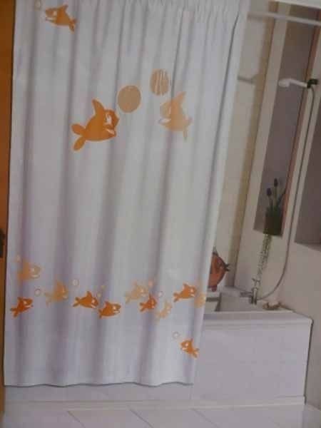 Una cortina de ducha blanca con peces naranjas.