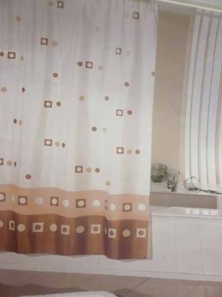 Una cortina de ducha marrón y blanca cuelga en un baño.