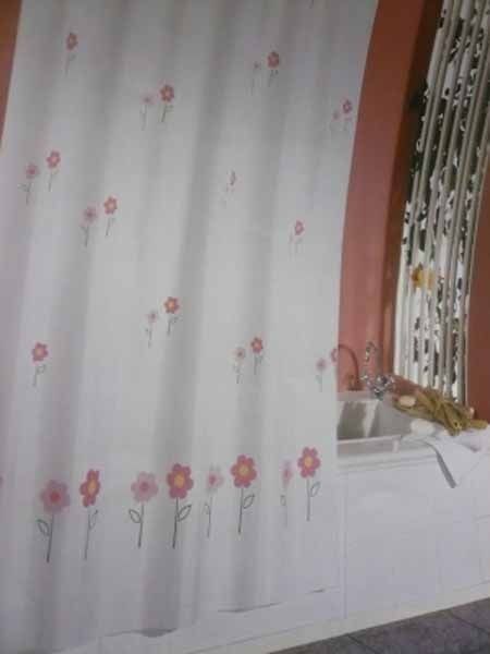 Una cortina de ducha con flores está en un baño al lado de un lavabo.