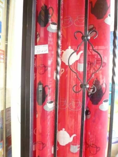 Una cortina roja con teteras y tazas sobre ella.