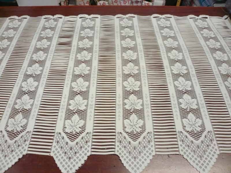 Una cortina de encaje blanco con hojas de arce.