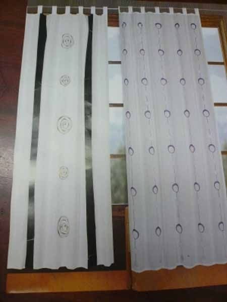 Dos cortinas blancas están colocadas una al lado de la otra sobre una mesa.