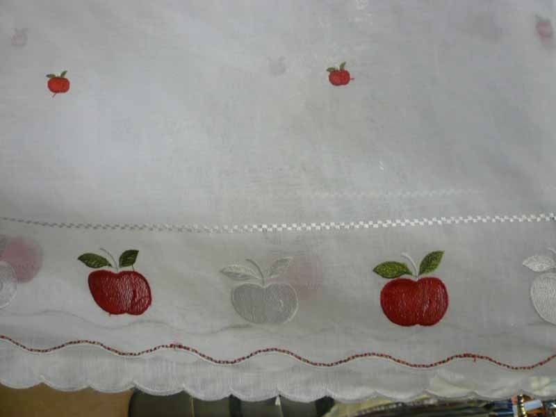 Una tela blanca con manzanas rojas bordadas