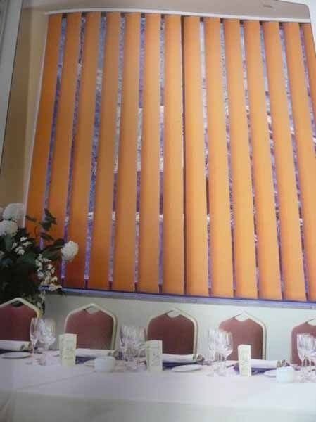 Una habitación con una mesa y sillas y una ventana con persianas verticales.