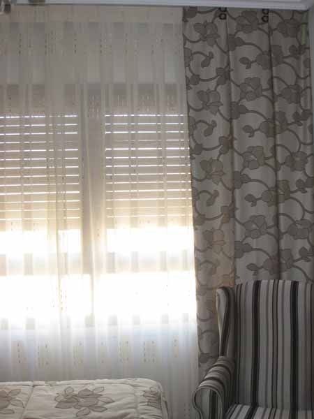 Un dormitorio con una cama, una silla y una ventana con persianas.