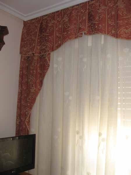 Un televisor está delante de una ventana con cortinas.