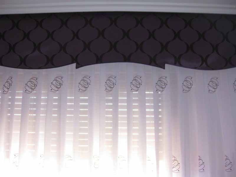 Una cortina blanca cuelga de una ventana con una pared violeta detrás de ella.