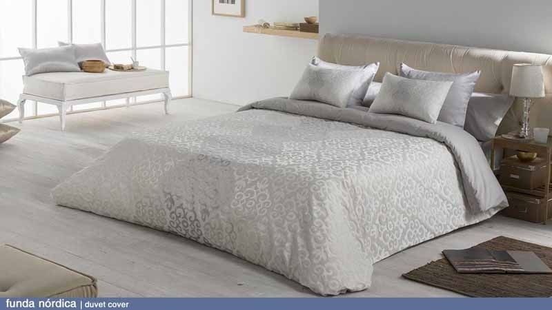 Una cama con un edredón blanco y almohadas en un dormitorio.