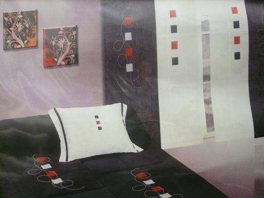 Una cama con un edredón negro y almohadas blancas