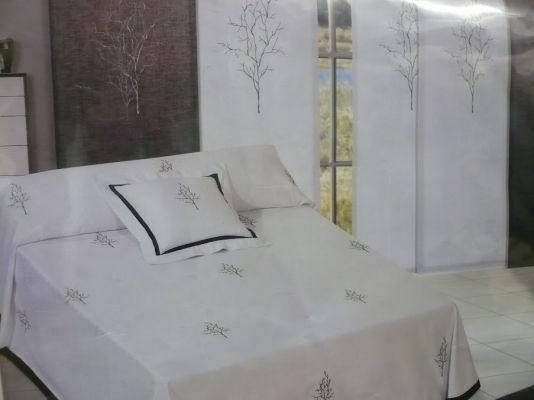 Una cama con un edredón blanco y almohadas en un dormitorio.