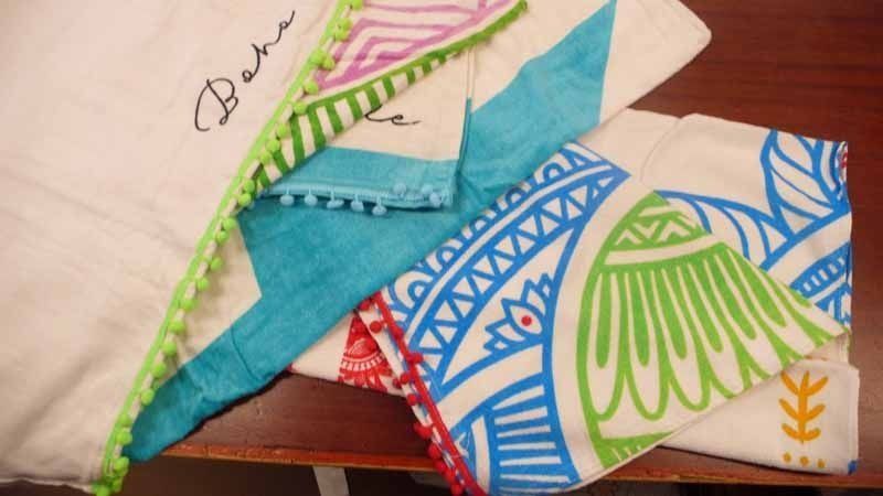 Hay tres toallas sobre una mesa de madera y una de ellas tiene el nombre Berta bordado.