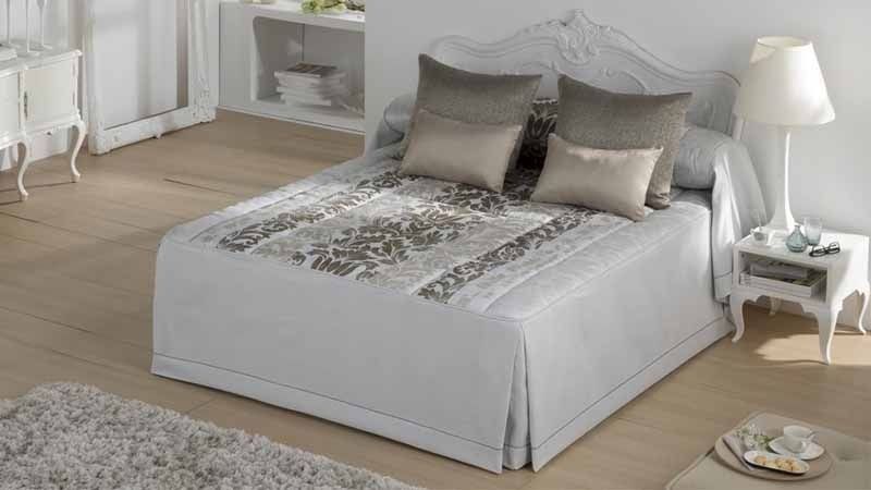 Una cama con un edredón blanco y almohadas en un dormitorio.