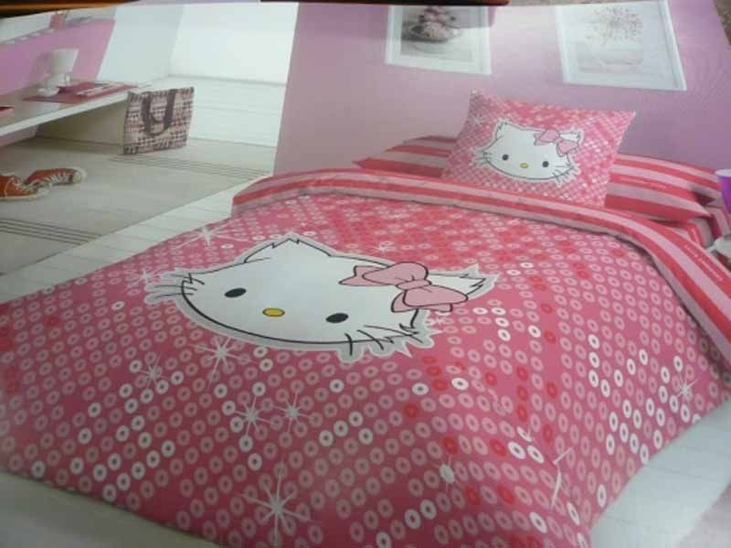 Una cama con un edredón y almohadas de Hello Kitty.