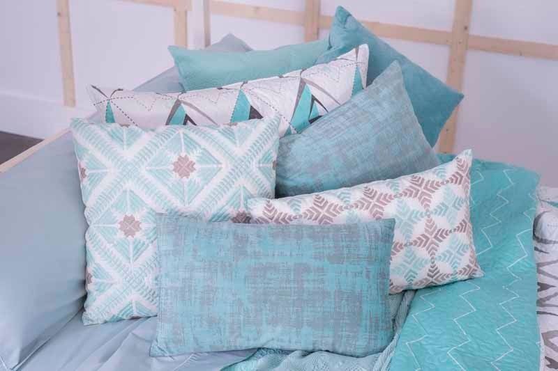 Una cama con muchas almohadas y una manta encima.