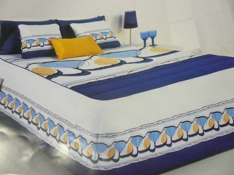 Una cama con una manta azul y blanca y almohadas