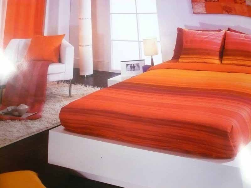 Una cama con sábanas y almohadas de rayas naranjas en un dormitorio.