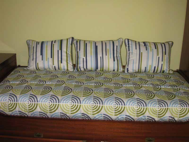 Una cama con una manta a rayas y almohadas encima.