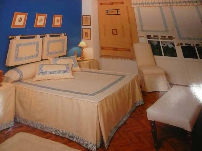 Un dormitorio con una cama y sillas y una pared azul.