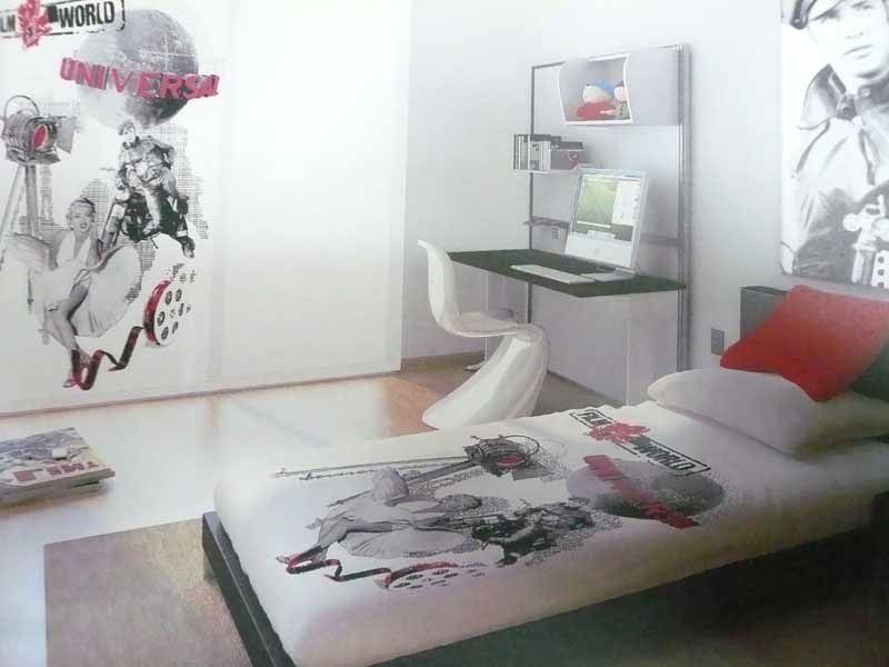 Un dormitorio con una cama, un escritorio y una pared que tiene la palabra universo.