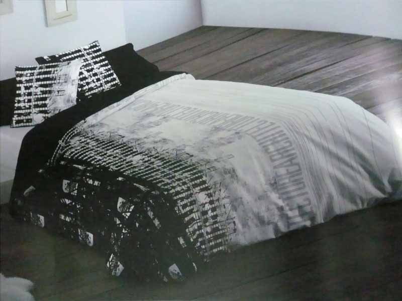 Una cama con edredón y almohadas en blanco y negro.