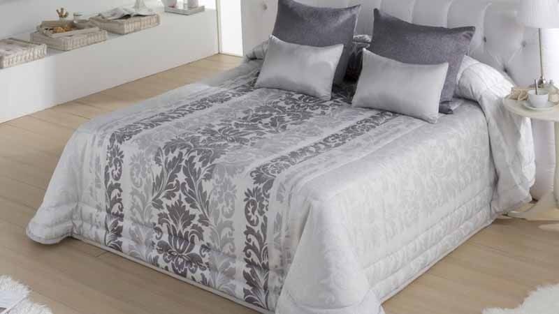 Una cama con un edredón y almohadas encima en un dormitorio.